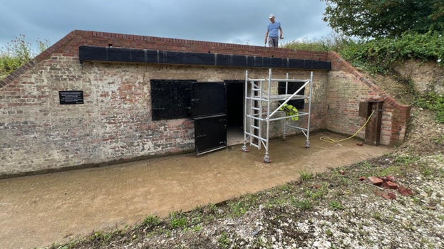 Image of a person standing on the roof of a low building with a parapet of new brickwork lining the roof